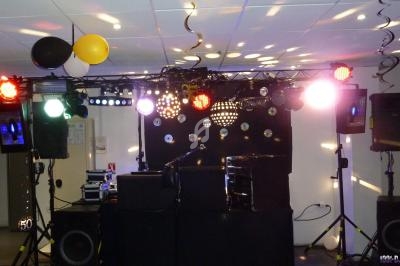 Installation de matériel de son et lumière pour une soirée, avec projecteurs colorés et décorations suspendues.