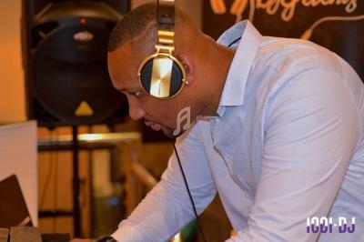 Un DJ portant un casque doré mixe de la musique sur un équipement audio dans un environnement intérieur.