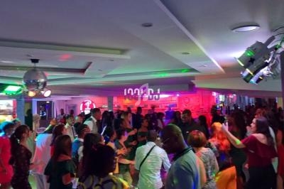 Groupe de personnes dans une salle animée avec éclairages colorés, musique et ambiance festive.