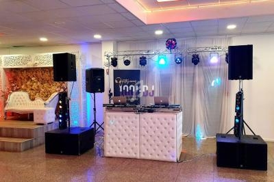 Installation de matériel de sonorisation et éclairage dans une salle de réception avec une table de mixage centrale.