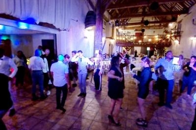 Des personnes dansent et discutent dans une salle de réception illuminée, avec une ambiance festive et conviviale.