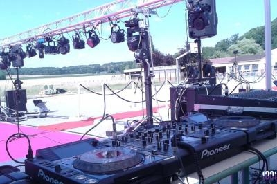 Matériel de sonorisation et d'éclairage installé en extérieur sur une scène avec vue sur un paysage rural.