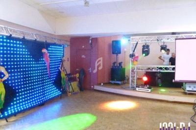 Salle de réception avec éclairage coloré, piste de danse, écran et équipement de sonorisation.