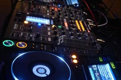 Table de mixage professionnelle avec platines, boutons et écrans lumineux, connectée à un ordinateur portable.