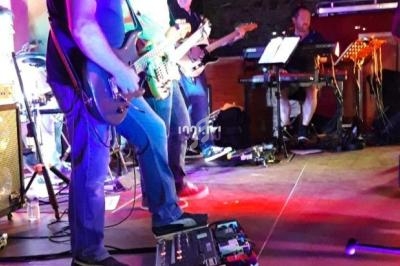 Musiciens jouant sur scène dans une ambiance lumineuse colorée, avec des instruments et des équipements visibles.