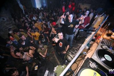 Vue plongeante d'une foule dans une salle de concert, avec un DJ et des platines au premier plan.