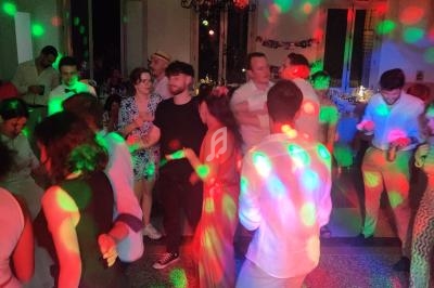 Groupe de personnes dansant sous des lumières colorées dans une salle éclairée, vue depuis une table de mixage.