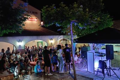 Groupe de personnes rassemblées en soirée autour d'une scène avec des équipements audio et un éclairage coloré.