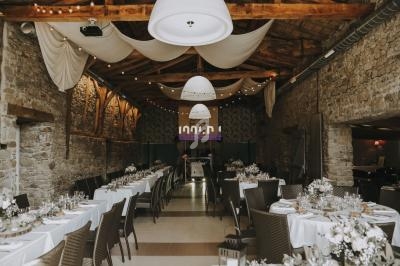 Salle de réception en pierre avec tables dressées, décorations suspendues et éclairage chaleureux.