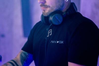 Un homme portant un casque audio autour du cou, concentré, dans un environnement éclairé par des lumières bleutées.