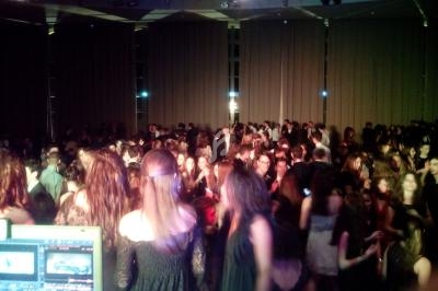 Groupe de personnes dansant dans une salle sombre avec des rideaux fermés, vue depuis une régie technique.