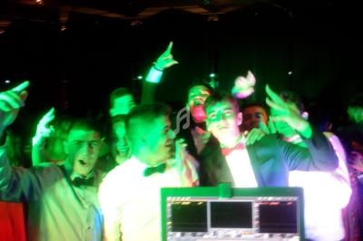 Groupe de jeunes en tenue de soirée dansant et s'amusant sous des lumières colorées dans une ambiance festive.