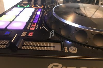 Table de mixage DJ avec platine, boutons lumineux et curseurs, utilisée pour la création ou le mixage musical.