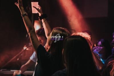 Personnes dans une ambiance festive, éclairées par des lumières colorées, lors d'un événement en intérieur.