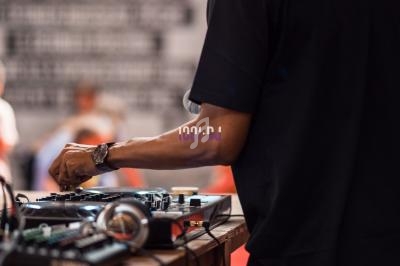 Un homme souriant mixe de la musique sur une table de mixage dans un espace intérieur.