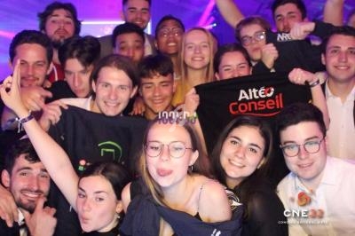 Un groupe de jeunes souriants posant ensemble lors d'un événement festif, certains tenant des t-shirts avec des logos.