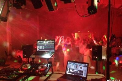 Vue d'une piste de danse animée avec des lumières colorées, des ordinateurs et une console de DJ au premier plan.