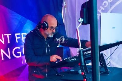 Un DJ portant un casque mixe de la musique sur une table de mixage dans un environnement éclairé par des lumières colorées.