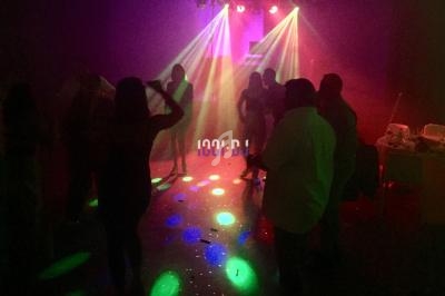 Personnes dansant sous des jeux de lumières colorées dans une ambiance festive et tamisée.