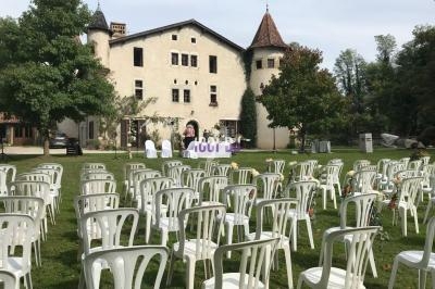 Chaises blanches disposées en rangées sur une pelouse devant un château, préparées pour une cérémonie en plein air.