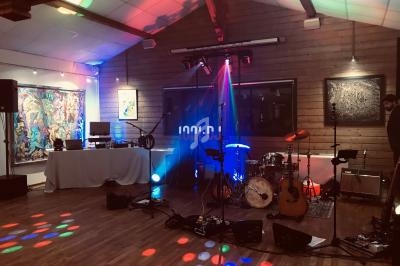 Salle de réception avec instruments de musique, éclairages colorés et espace DJ préparés pour un événement.