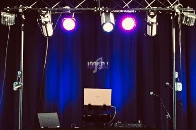 Installation de matériel de DJ avec ordinateurs, projecteurs lumineux et rideau bleu en arrière-plan.