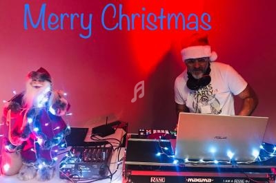 Un DJ portant un bonnet de Noël mixe de la musique à côté d'une figurine de Père Noël illuminée.