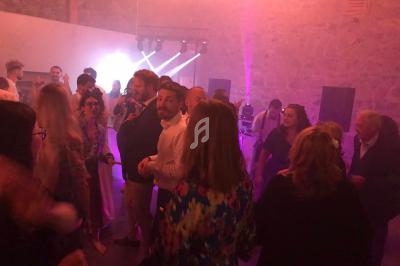 Groupe de personnes dansant dans une salle éclairée par des lumières colorées et une ambiance festive.