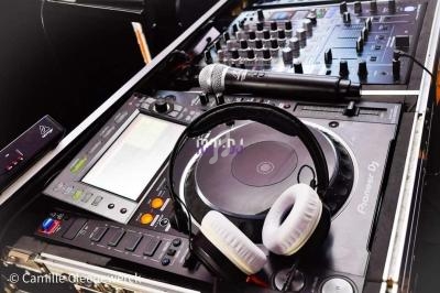 Équipement de DJ comprenant une table de mixage, un casque audio et des microphones posés sur une console.