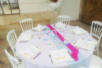 Table ronde dressée pour un événement, avec nappes blanches, chemins de table colorés et décorations élégantes.