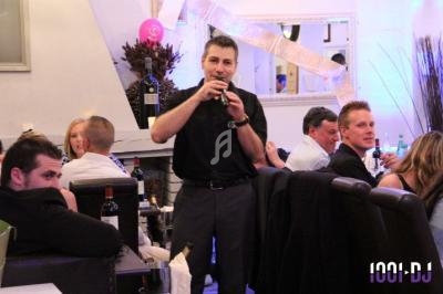 Un homme parlant dans un micro dans un restaurant, entouré de convives assis à des tables.