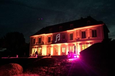 Façade d'un grand bâtiment éclairé par des lumières colorées dans un environnement nocturne.