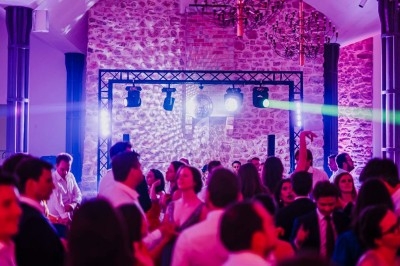 Personnes dansant sous des lumières colorées dans une salle en pierre avec une ambiance festive.