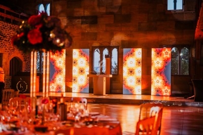Salle de réception décorée avec des panneaux lumineux étoilés, des tables dressées et des murs en pierre apparente.