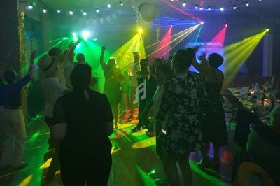 Personnes dansant sous des éclairages colorés dans une salle de fête décorée.