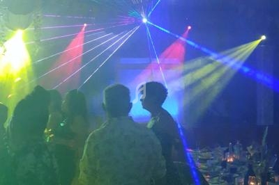 Personnes dansant sous des jeux de lumières colorées dans une ambiance festive et enfumée.