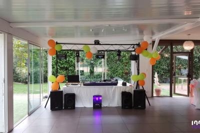 Installation de matériel de sonorisation et éclairage avec ballons colorés dans une salle lumineuse ouverte sur un jardin.