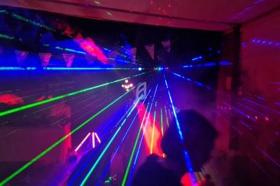 Jeux de lumières laser multicolores dans une ambiance sombre avec des silhouettes en arrière-plan.