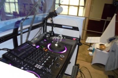 Table de mixage avec platines, microphone et éclairage violet, installée dans un espace intérieur.