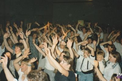 Foule enthousiaste levant les bras lors d'un événement festif dans une salle bondée.
