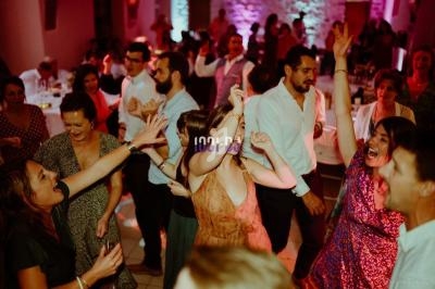 Des personnes dansent et s'amusent lors d'une fête dans une salle éclairée par des lumières colorées.