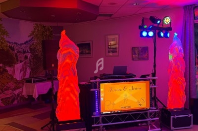 Poste de DJ avec éclairage coloré et décor lumineux dans une salle de réception.