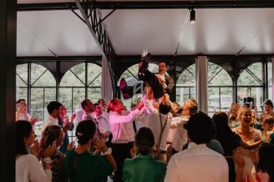 Un groupe de personnes porte un homme en costume dans une salle lumineuse lors d'une célébration festive.