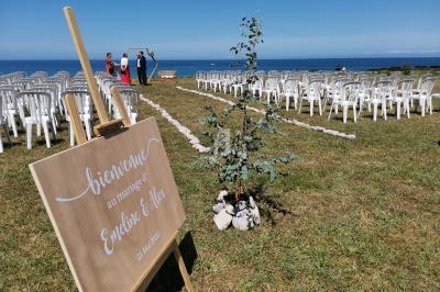 Cérémonie de mariage en plein air avec des chaises alignées, un panneau de bienvenue et vue sur la mer.