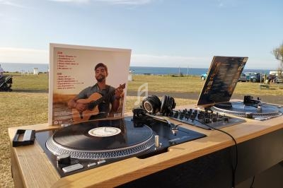 Platines vinyles et casque audio installés en extérieur, avec une pochette d'album montrant un homme jouant de la guitare.