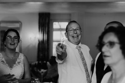 Un homme souriant pointe du doigt dans une salle, entouré de plusieurs personnes lors d'un événement.