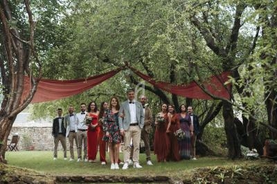 Un groupe de personnes posant sous des arbres avec des drapés rouges, dans un cadre extérieur verdoyant.