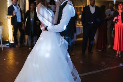 Un couple danse sous des lumières tamisées lors d'une réception de mariage dans une salle éclairée.