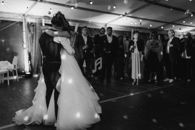 Deux personnes dansent enlacées sous une tente éclairée, entourées d'invités observant la scène.