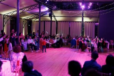 Salle de réception illuminée avec des invités assis et debout, certains tenant des bâtons lumineux.